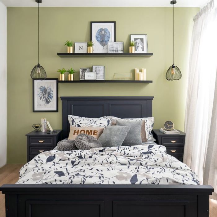 Bedroom with a dark bed frame against a green wall